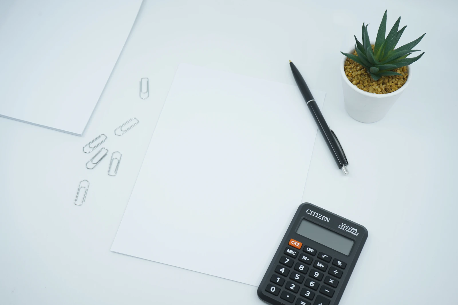A calculator, pen, and paperwork on a desk
